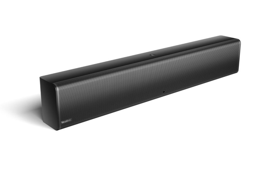 A black Yealink MSpeaker II, a rectangular soundbar, is angled slightly to the right against a white background, casting a soft shadow to its left. The speaker grille, featuring a fine, perforated pattern, covers the entire front surface. The Yealink logo is visible on the far left of the grille. A small, circular indicator light is subtly located near the center bottom edge. The device appears sleek and modern.