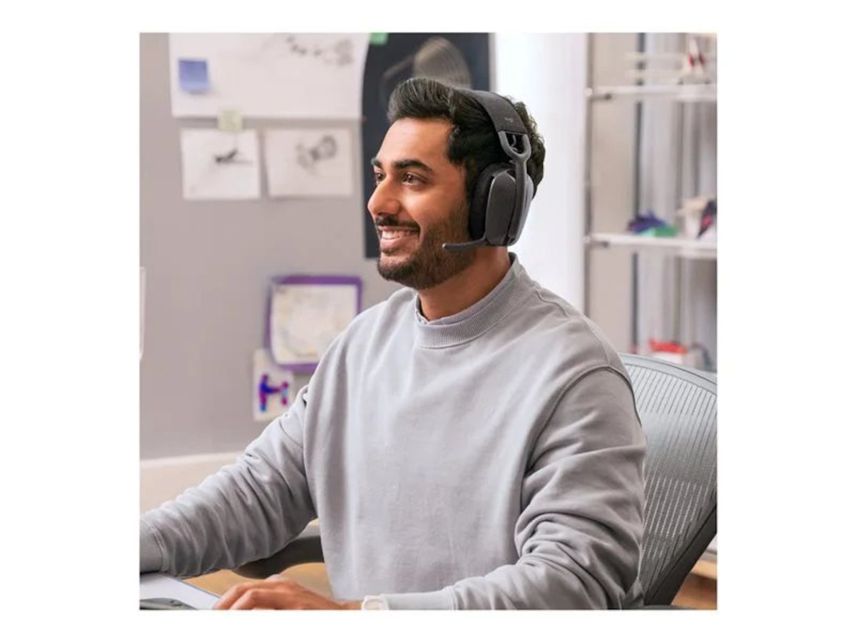 Man wearing a black wireless headset with a boom mic during a video call at work.