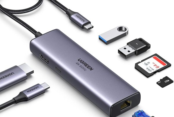 UGREEN space gray USB-C hub displaying multi-port connectivity, surrounded by a braided USB-C cable, HDMI connector, USB flash drives, full-size SD card, microSD card, and an Ethernet cable.