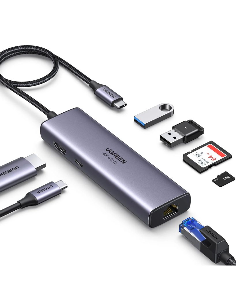 UGREEN space gray USB-C hub displaying multi-port connectivity, surrounded by a braided USB-C cable, HDMI connector, USB flash drives, full-size SD card, microSD card, and an Ethernet cable.